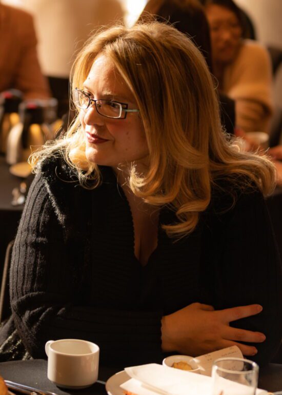 Picture of a woman sitting at a table during a networking event, by Seb Duper.