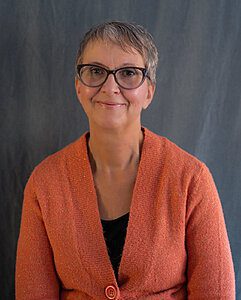 A portrait of Sue Pitchforth wearing an orange vest, by Seb Duper