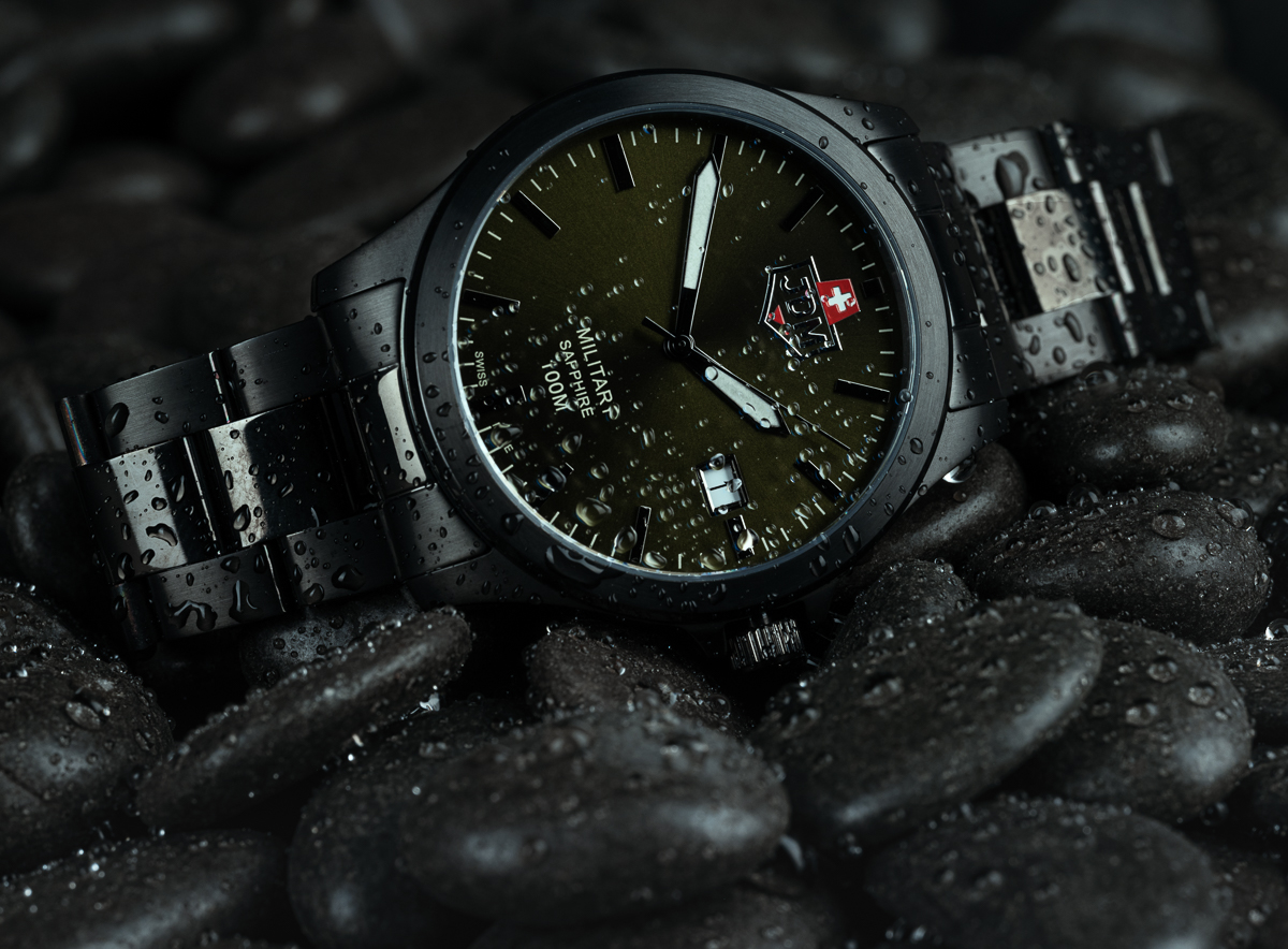 A wet JDM Military Sapphire men's watch sitting on pebbles, a photo by Seb Duper.