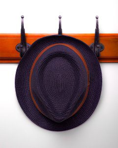 A hat hanging from a coat rack, a photo by Seb Duper