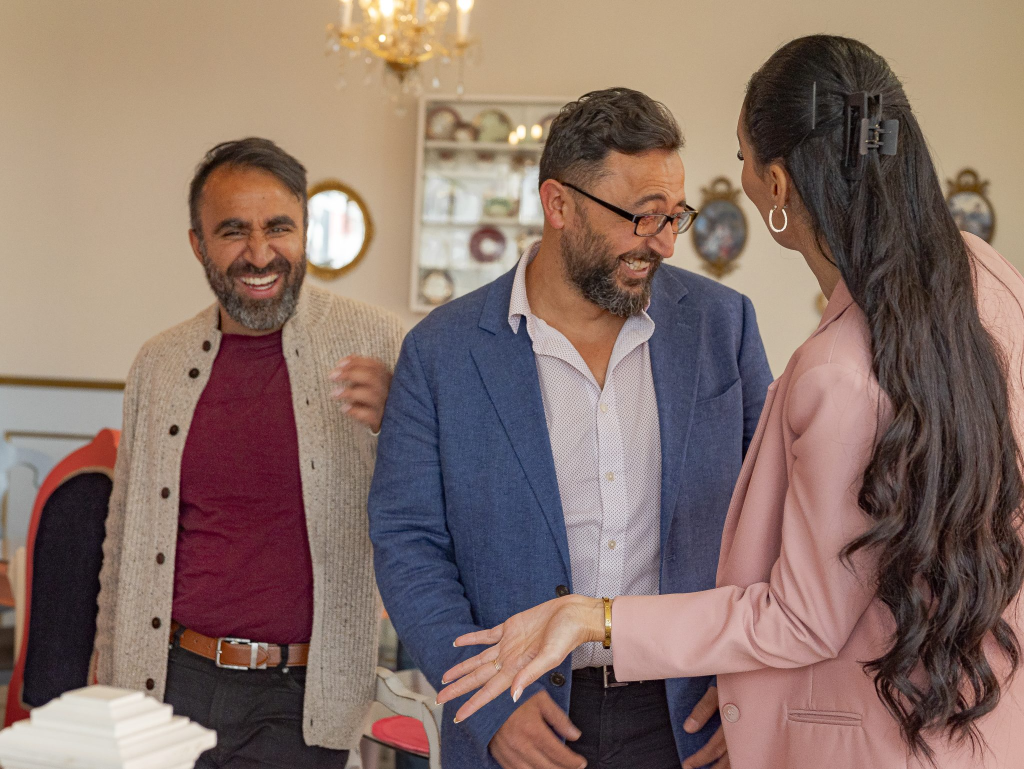 Two men and a woman laughing in a café setting.