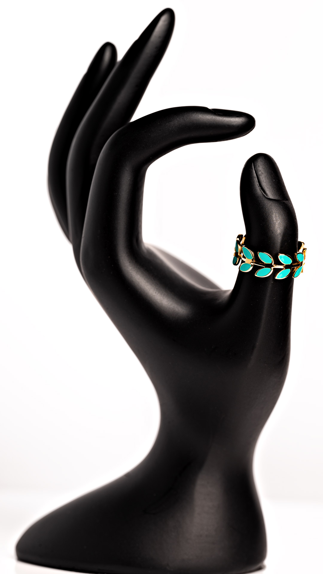 A plastic hand, painted black, with fingers curled. A small turquoise ring rests on the thumb. Product photography by Seb Duper.