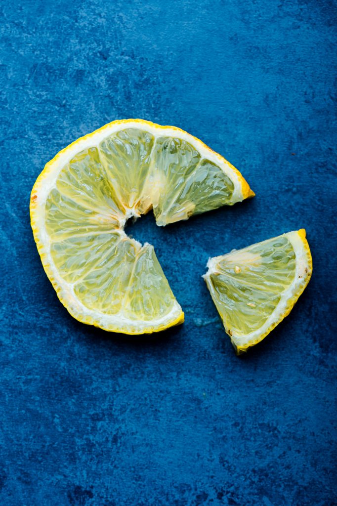 A slice of lemon resting on a blue background, with a triangle cut out from it.