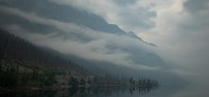 Fog and mist float above a lake, shrouding the mountains in the backdrop. Jasper, Alberta, Canada.