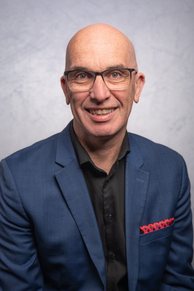 A headshot of an Ottawa entrepreneur, dressed in a black shirt with a dark blue sport jacket and a red pocket square.
