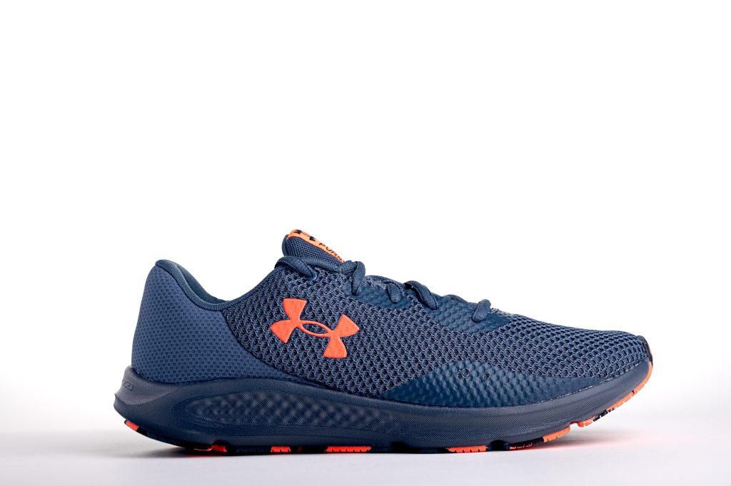 A single Under Armour sneaker, deep blue with bright orange highlights, against a white background.